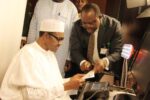 Chris Onyemenam, the Director-General of National Identity Management Commission (NIMC), on the right speaks with President Muhammadu Buhari, during the data capture of the President in Abuja